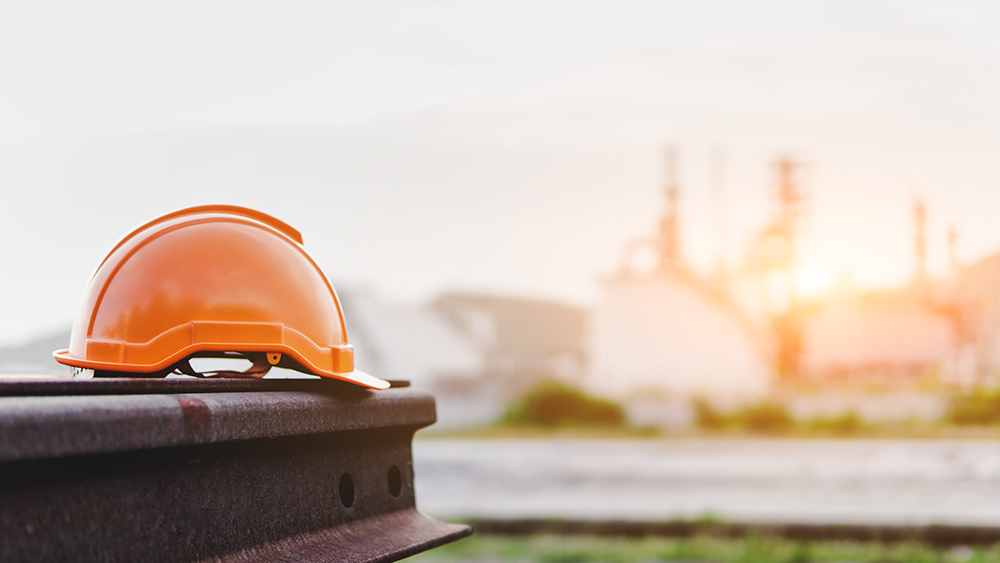 an orange hard hat is sitting in the foreground with a construction site in the background